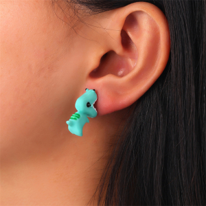 Close-up of the green dinosaur earrings worn by a model, highlighting the vibrant colour and fun character-shaped design.