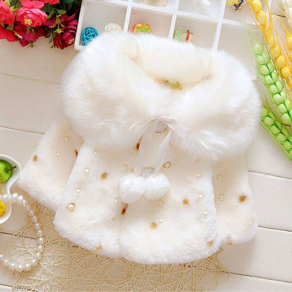 White faux fur winter coat for girls displayed on a table, warm and stylish outerwear.