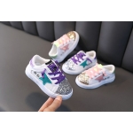 Four pairs of glitter trainers for baby girls displayed on a dark sofa, featuring sparkling designs perfect for little adventurers.