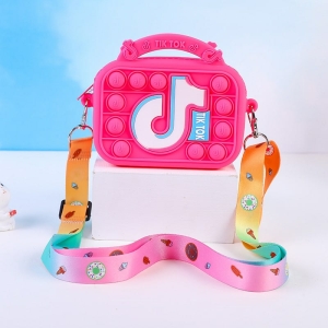 A dark pink silicone TikTok-themed Pop It handbag on a white table, featuring the TikTok logo, pop-it balls, and a colourful strap.