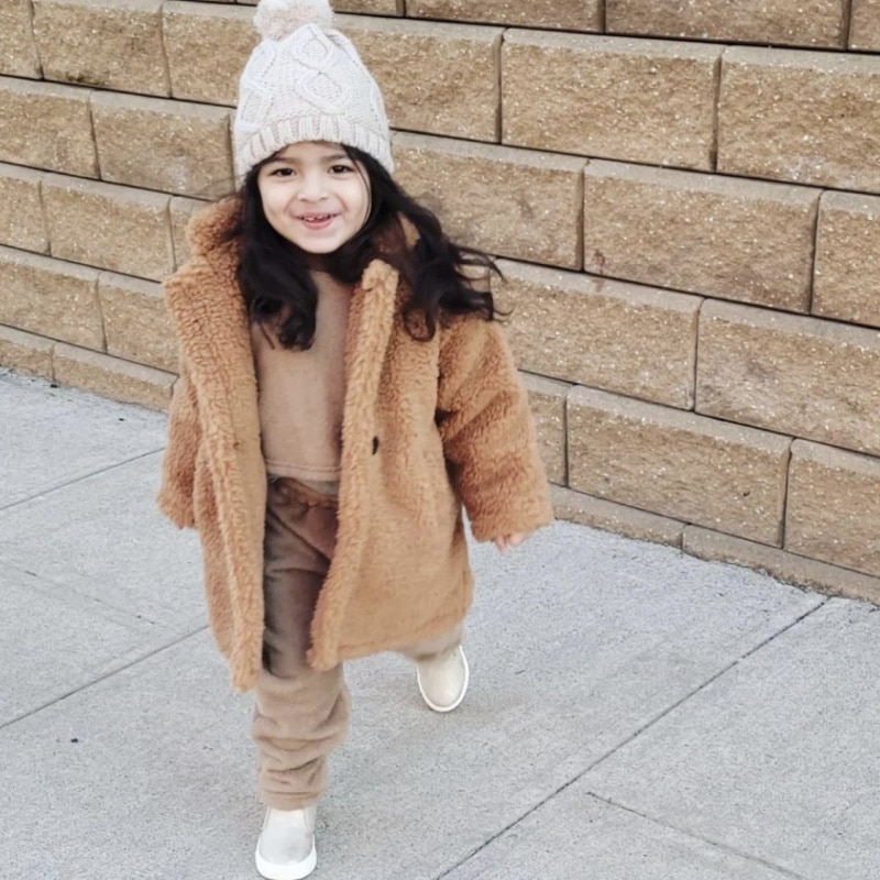 A girl wearing the thick faux fur winter jacket, showing the cosy fit, plush texture, and stylish look for cold winter days.