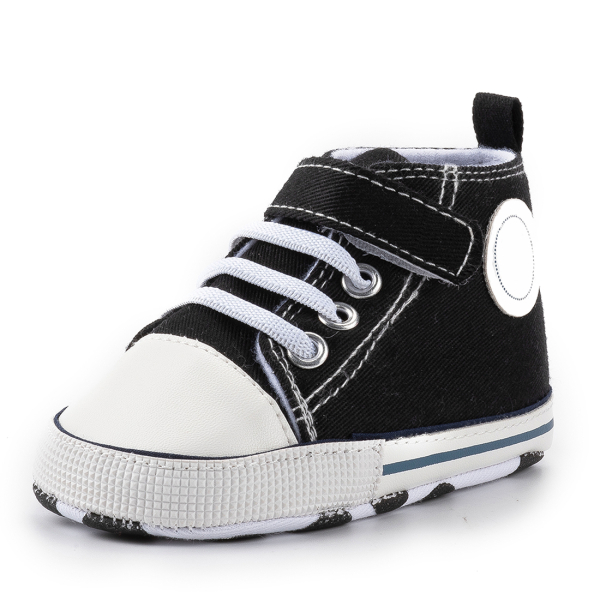 Close-up of the Velcro strap on girls black Converse-style trainers, showing the easy-fasten design and classic black canvas.
