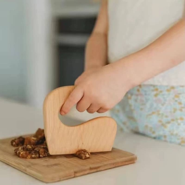 A safe and educational Montessori mini wooden knife for girls from age 2, designed for food preparation play and developing fine motor and life skills.