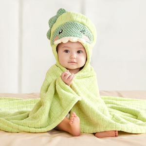 Baby sitting up wearing a green animal hooded bath robe, looking cosy and content