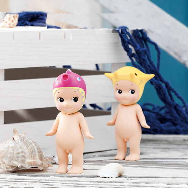 Two Sonny Angel marine theme figurines beside a white wooden palette and blue net, capturing a charming seaside scene for collectors and fans.