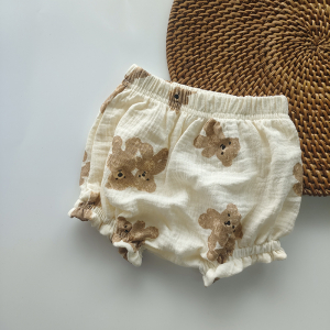 A colourful summer cotton bloomer for girls featuring a fun bear and rainbow print, displayed on a white styled table with rope decor.