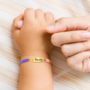A baby's wrist wearing a colourful braided ID bracelet beside an adult's hand, showing the delicate and personalised jewellery piece for little girls.