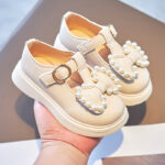 A pair of loafers for girls featuring a charming bow tie detail surrounded by pearls on top, a sweet and playful shoe perfect for parties and special occasions.