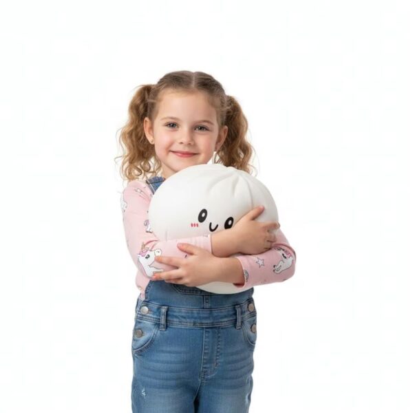 Young girl with pigtails hugging a large white squishy dumpling, wearing jeans and a pink t-shirt, showing the giant soft toy's size.