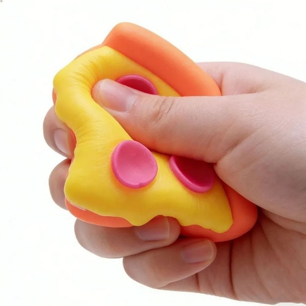 View of the Needoh pizza slice squishy toy next to its black packaging, showing the fun pizza shape and colours of this stress-relief toy.